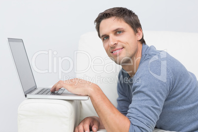 Smiling young man using laptop in living room