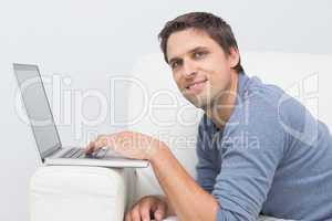 Smiling young man using laptop in living room