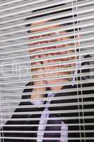 Businessman with head in hands in front of blinds in office