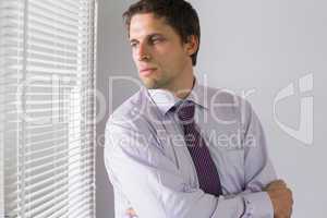 Serious businessman peeking through blinds in office