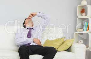 Tired businessman sitting on sofa in living room