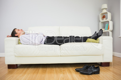 Tired businessman sleeping on sofa in living room
