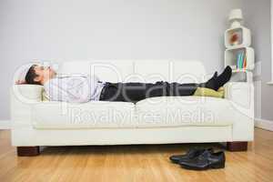 Tired businessman sleeping on sofa in living room