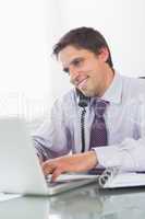 Businessman using telephone and laptop at desk