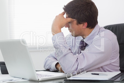 Worried businessman with laptop sitting in office