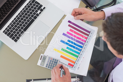 Businessman with laptop and graph at office desk