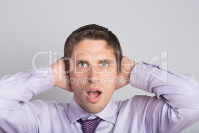 Green eyed businessman with hands covering ears