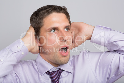 Green eyed businessman with hands covering ears
