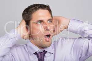 Green eyed businessman with hands covering ears