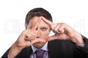 Close-up of businessman looking through finger frame