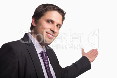 Businessman giving a welcome gesture against white background