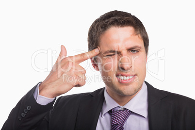 Businessman holding fingers against temple in gun gesture