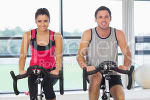 Young man and woman working out at spinning class