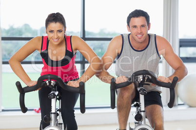 Young man and woman working out at spinning class
