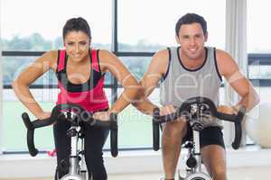 Young man and woman working out at spinning class