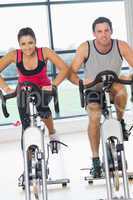 Young man and woman working out at spinning class