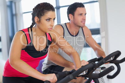 Young man and woman working out at spinning class