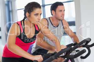 Young man and woman working out at spinning class