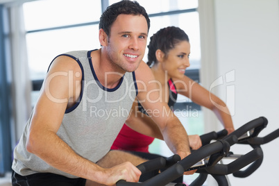 Young man and woman working out at spinning class