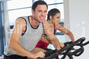 Young man and woman working out at spinning class