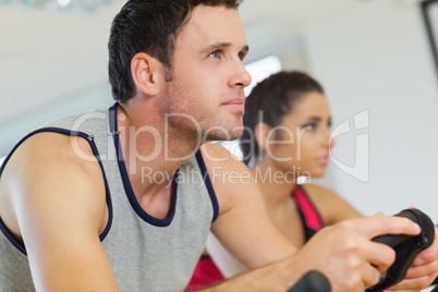 Yyoung man and woman working out at spinning class