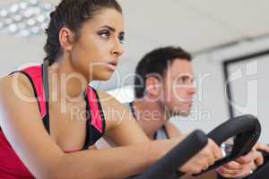 Young man and woman working out at spinning class