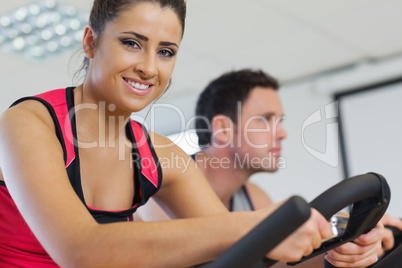 Young woman and man working out at spinning class