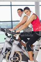 Young woman and man working out at spinning class