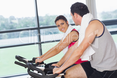 Young woman and man working out at spinning class