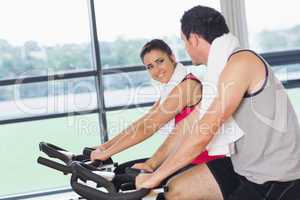 Young woman and man working out at spinning class