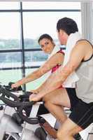 Young woman and man working out at spinning class