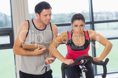 Trainer watching woman work out at spinning class