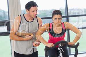 Trainer watching woman work out at spinning class