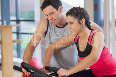 Trainer helping woman work out at spinning class