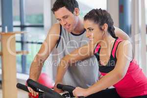 Trainer helping woman work out at spinning class