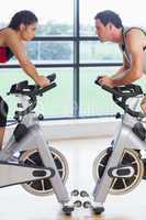 Side view of a woman and man working out at spinning class
