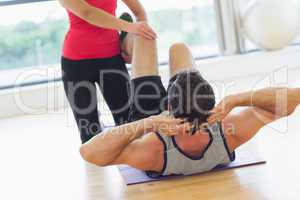 Female trainer assisting man with his exercises in gym
