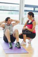 Female trainer looking at man do abdominal crunches