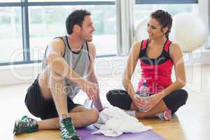 Woman and man with water bottles chatting at gym