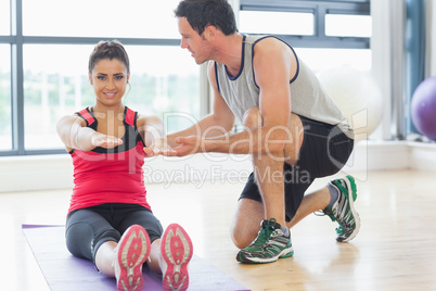 Male trainer assisting woman with pilate exercises in fitness st