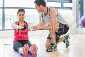 Male trainer assisting woman with pilate exercises in fitness st