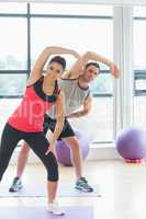 Portrait of two sporty people stretching hands at yoga class