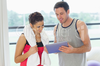 Fit couple looking at digital table in exercise room