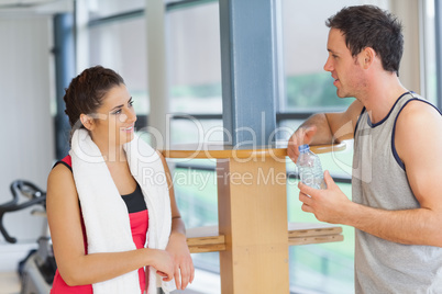 Woman and man with water bottle chatting at gym