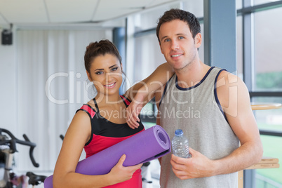 Fit couple with water bottle and exercise mat in exercise room