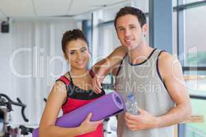 Fit couple with water bottle and exercise mat in exercise room