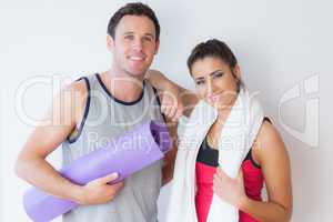 Portrait of a fit young couple with towel and exercise mat