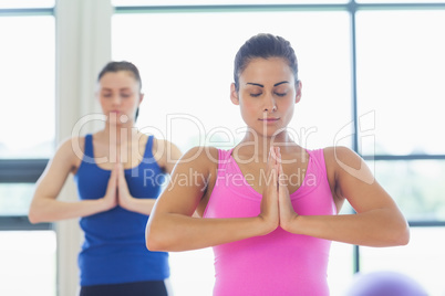 Two sporty young women in Namaste position with eyes closed