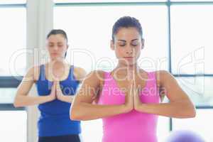Two sporty young women in Namaste position with eyes closed