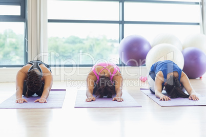 Fit women bending over on exercise mats in fitness studio